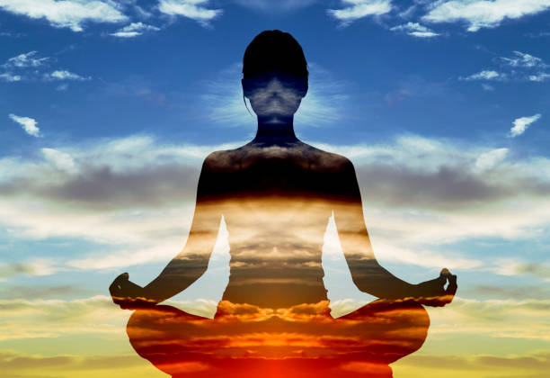 woman doing yoga in lotus position over sunset sky